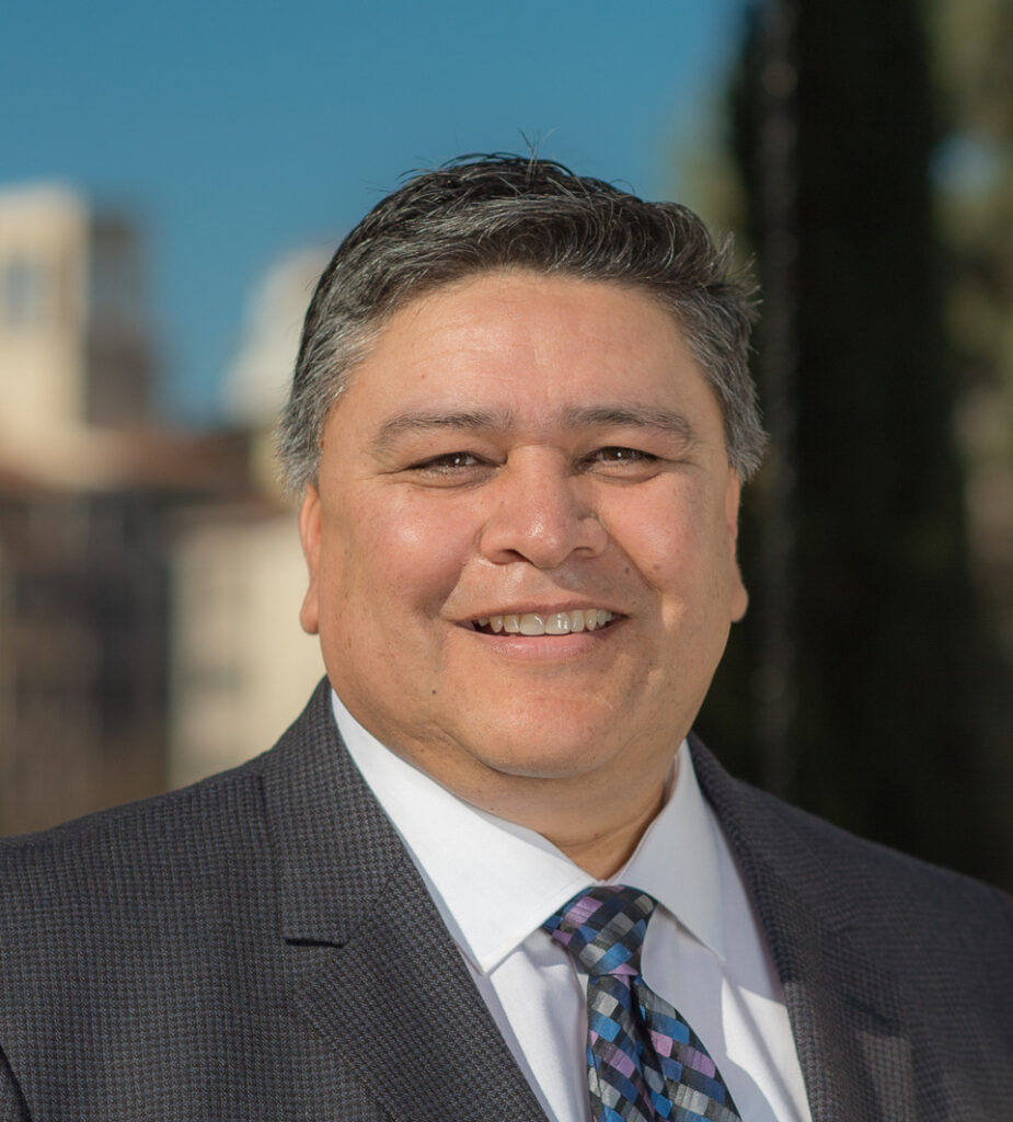 A man in suit and tie smiling for the camera.