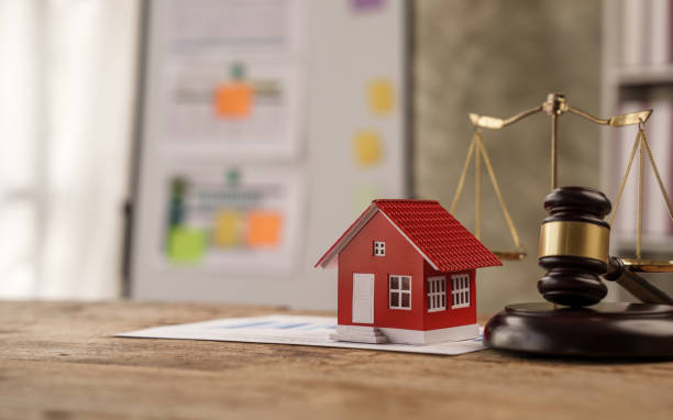 A red house sitting on top of paper next to a scale.